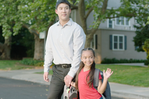 OTS Go Safely video still of father and daughter holding hands while crossing residential street