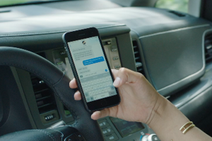 Driver of car holding cell phone in right hand texting while driving